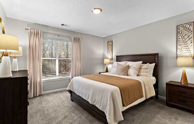A bedroom with a large bed and a window with curtains.