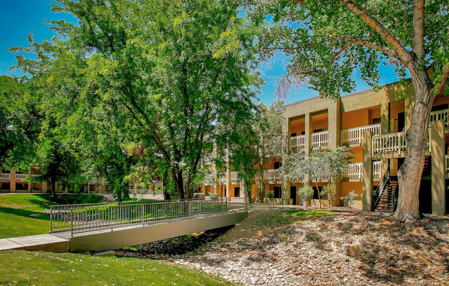 a bridge over a pond in front of a building with trees