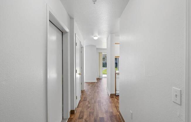 a hallway with white walls and white doors and a hard wood floor