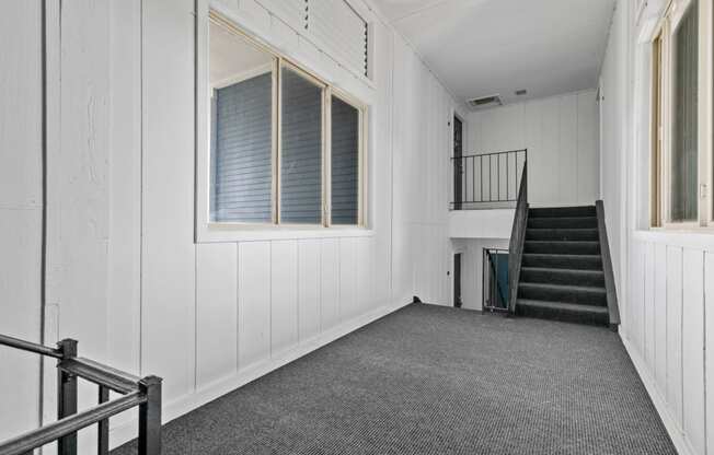 a large white room with a staircase and a window