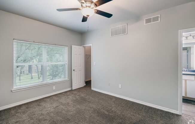 an empty living room with a ceiling fan and a window