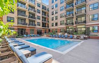A large outdoor pool with lounge chairs and a building in the background.