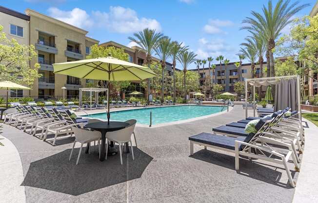 A poolside area with sun loungers and umbrellas at The Kitt at Warner Center Apartments, Woodland Hills