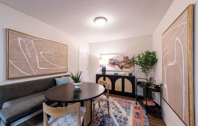 A living room with a grey couch, a round table, and a painting on the wall.