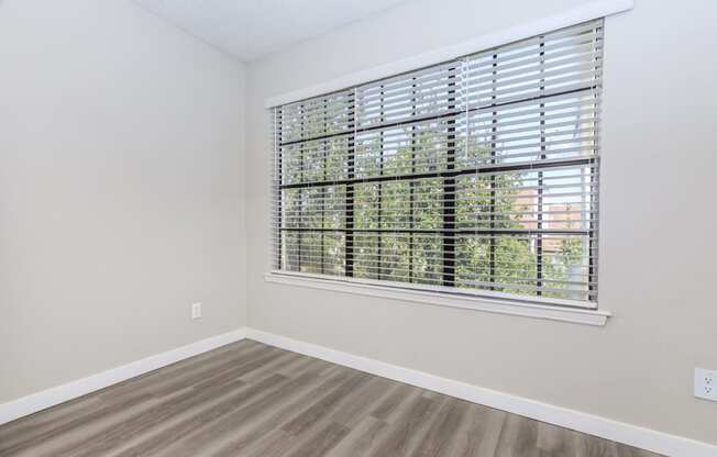 a bedroom with a large window and hardwood floors