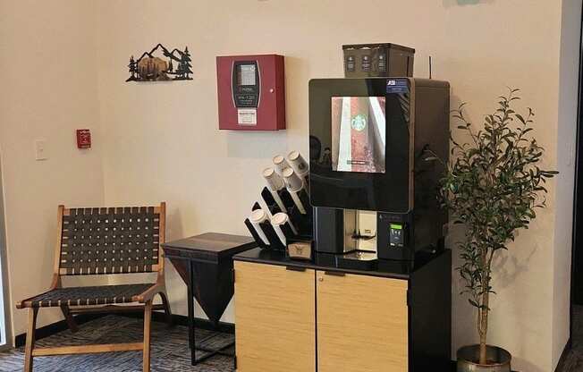 A wooden chair sits in front of a coffee machine and a vending machine.