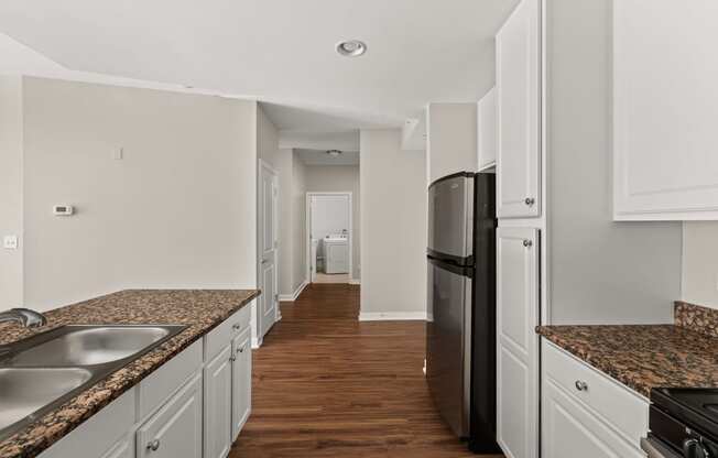 a kitchen with white cabinets and granite counter tops and a black refrigerator