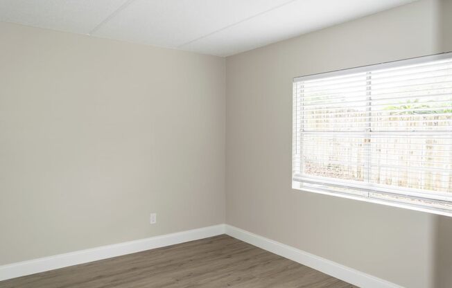 an empty room with a large window and wooden floors