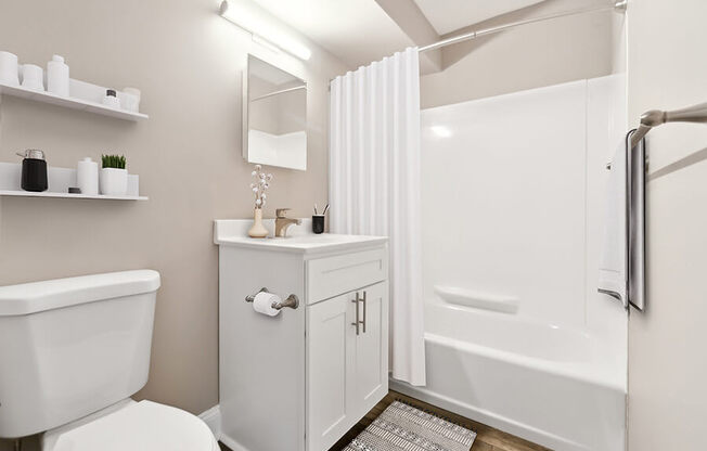 Model Bathroom with White Cabinets, Wood-Style Flooring and Shower/Tub at Heights at Marlborough Apartments located in Marlborough, MA.