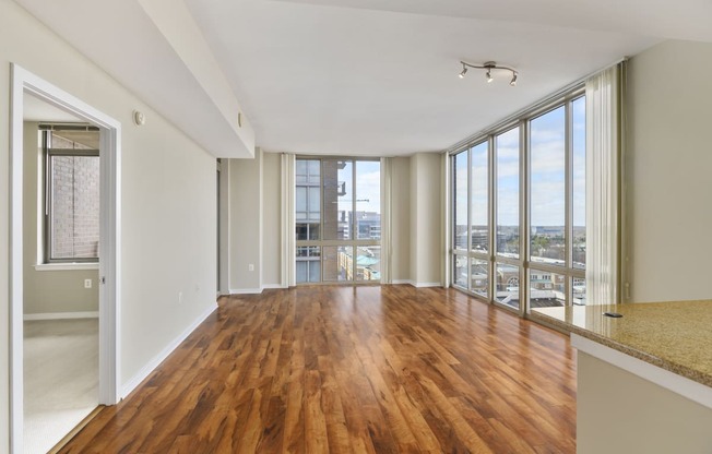 an empty living room with wood flooring and large windows