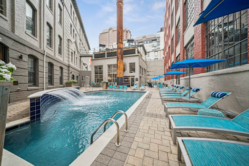 A pool with a waterfall and lounge chairs.