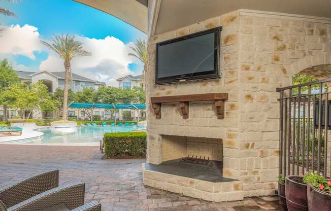 A patio with a stone fireplace and a television mounted on the wall.