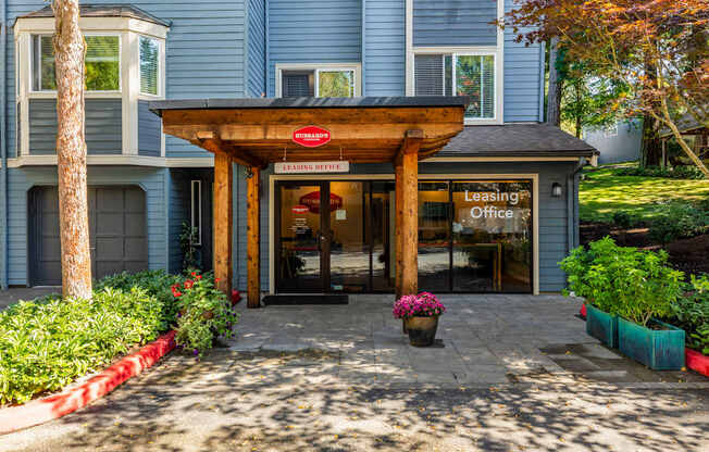 A leasing office is situated in front of a blue building.
