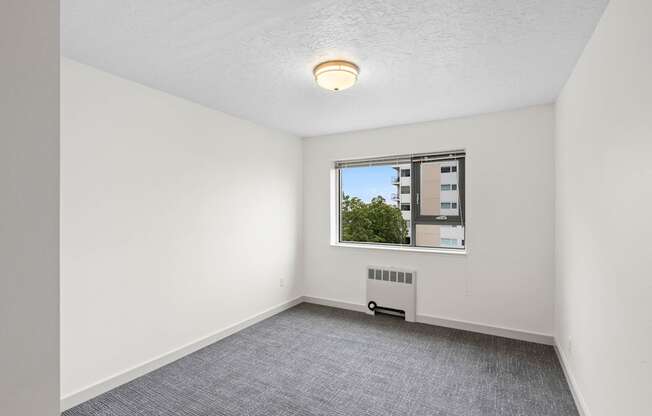 an empty living room with a window and white walls