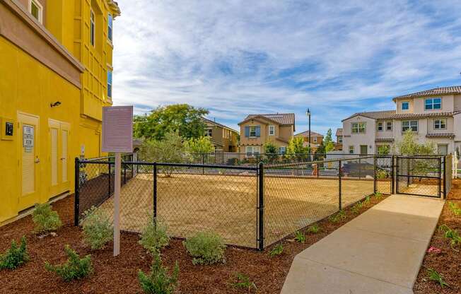 A yellow building with a black fence and a sign in front of it.