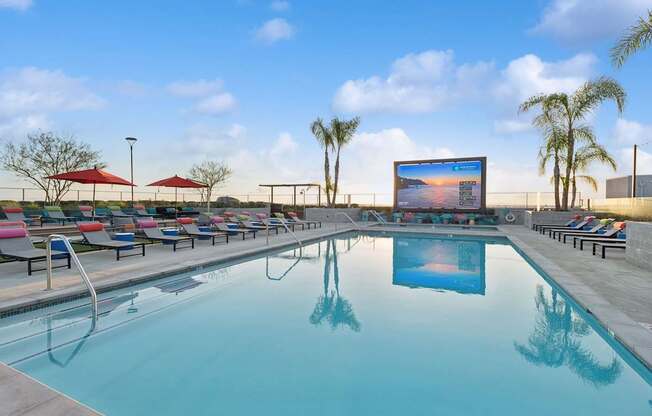 A large screen is mounted on a wall above a swimming pool.