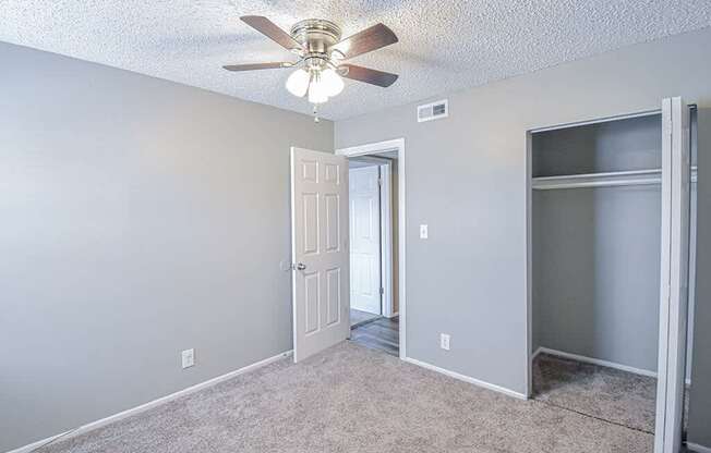 an empty room with a ceiling fan and a door to a closet