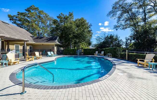 A round swimming pool surrounded by a wooden deck and lounge chairs.