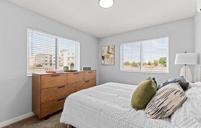 a bedroom with a bed and two windows