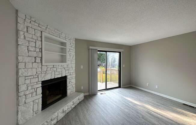 an empty living room with a stone fireplace