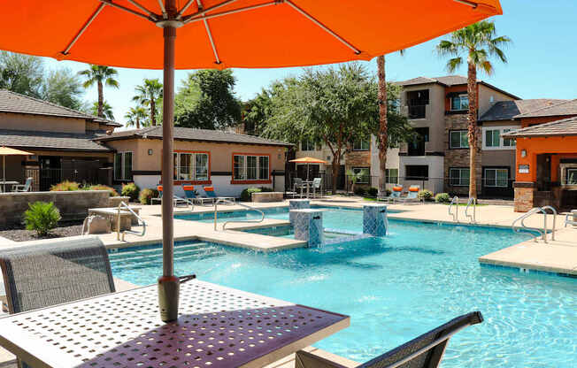 A pool with a table and chairs and an orange umbrella.