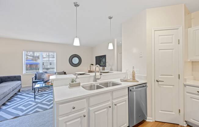 a kitchen with an island and a living room in the background