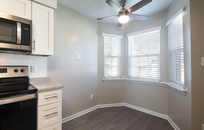 an empty kitchen with a large window and a ceiling fan