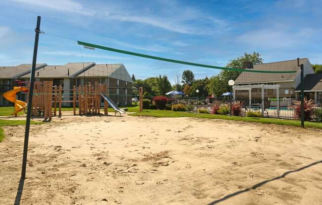 a sand volleyball court in a park with houses in the background