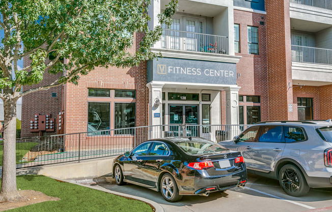 two cars parked in front of a fitness center