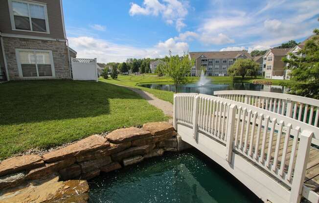 This is a picture of a bridge, pond with a fountain and  building exteriors at Nantucket Apartments, in Loveland, OH.