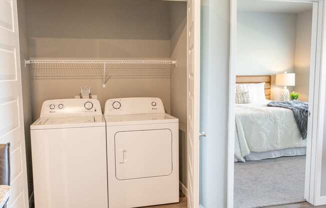 a room with a washer and dryer and a bedroom with a bed at Technology Park Apartments, Minnesota