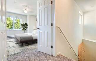 A white door is open in a room with a bed and a plant.