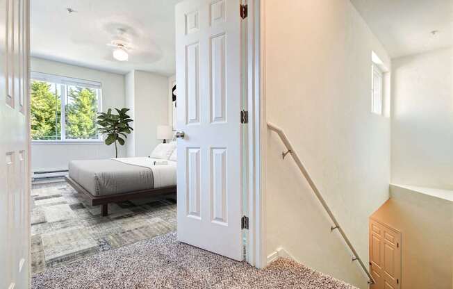 A white door is open in a room with a bed and a plant.