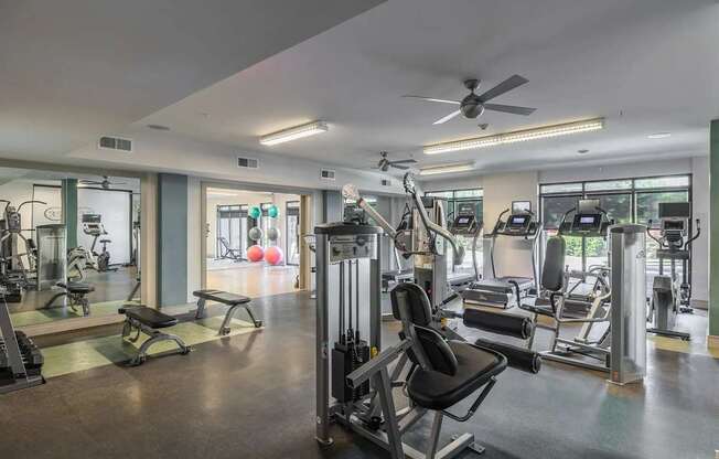 A gym with a variety of equipment including treadmills, weights, and exercise machines.