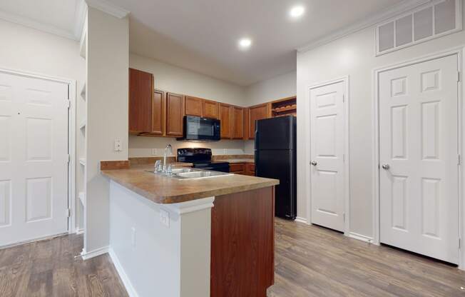 Spacious kitchen with hardwood style flooring and black appliances