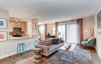 a living room with a couch coffee table and chairs and a kitchen in the background