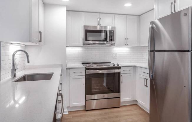 a kitchen with white cabinets and stainless steel appliances at Avenue Two Apartments, California, 94063