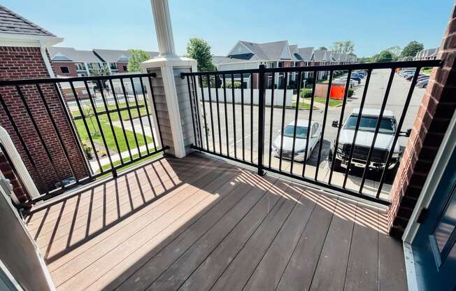 a balcony with a wooden floor and a black railing with a balcony fence