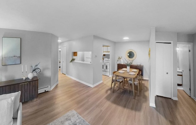 a living room and dining room with white walls and wood floors