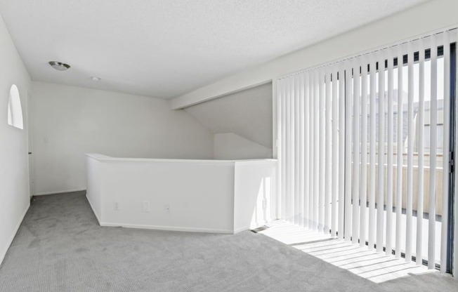 an empty living room with white blinds and a window