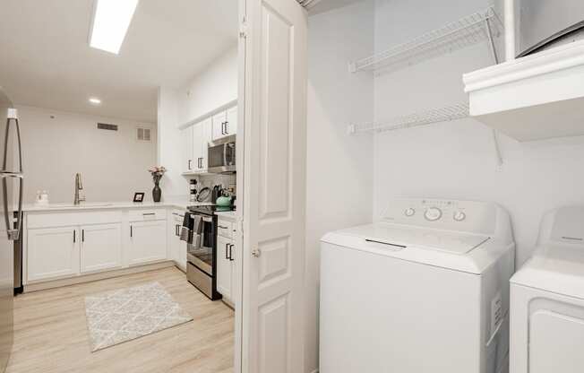 a laundry room with a washer and dryer and a kitchen with white appliances