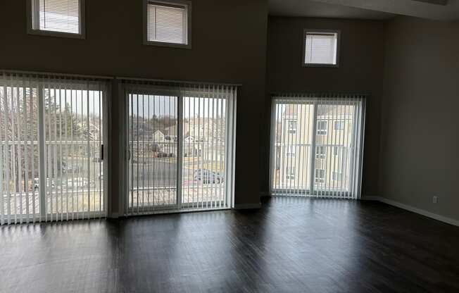 an empty living room with sliding glass doors and wood floors