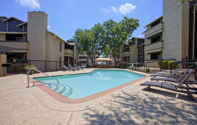 A swimming pool surrounded by apartment buildings on a sunny day.