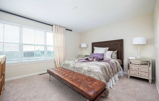 A bedroom with a bed, nightstand, and window with blinds.