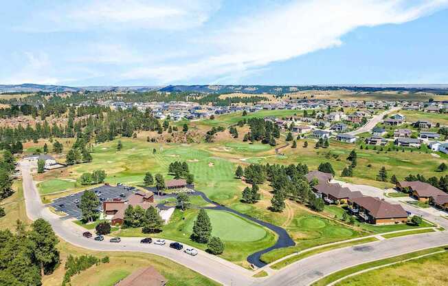 A golf course with a clubhouse and houses in the background.