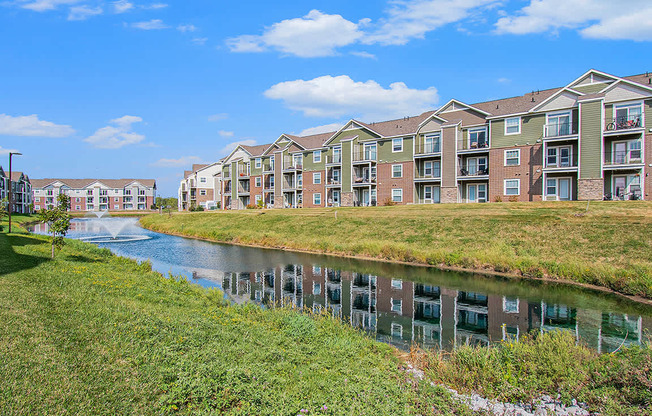 An apartment building is reflected in the water of a pond at Strathmore Apartment Homes, West Des Moines, IA