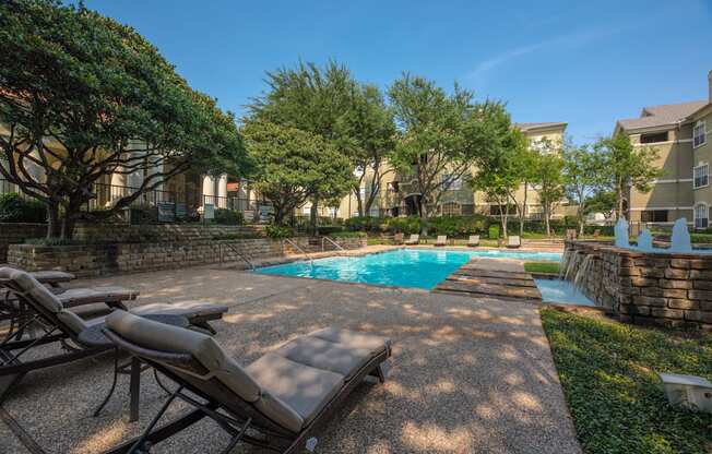 A pool surrounded by trees and chairs.