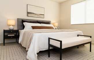 a bedroom with a bed and two nightstands and a window