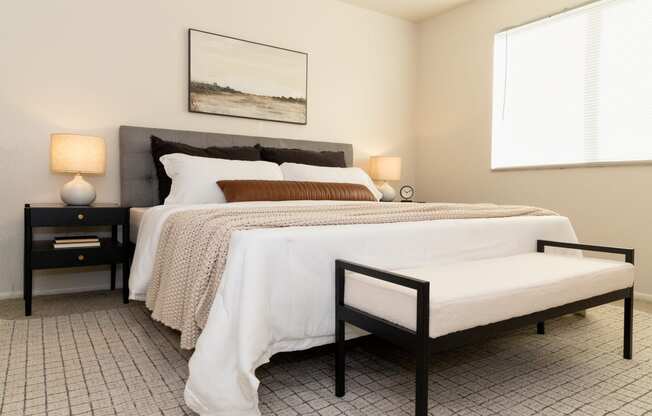 a bedroom with a bed and two nightstands and a window