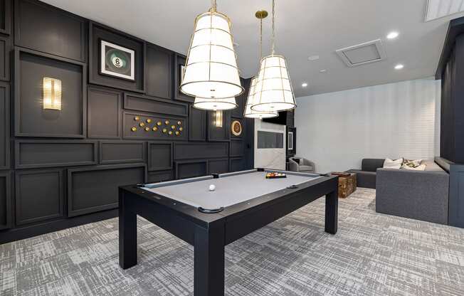 a billiards table in a game room with three lamps